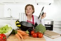 Home cook woman in red apron at domestic kitchen holding cooking pot with hot soup smelling vegetable stew Royalty Free Stock Photo