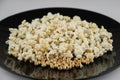 Home-cooked in the microwave the popcorn in a black bowl on white, front view, close, short focus