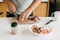 Home cooking concept. Person cutting onion and chicken fillet with knife on wooden board on modern white kitchen. Process of Royalty Free Stock Photo