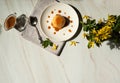 Delicious rice pudding with pumpkin, caramel sauce and yellow forsythia flowers on a background of pastel green marble.