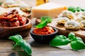 Home cooking - raw tortellini pasta with tomato pesto and sun-dried tomatoes and basil Royalty Free Stock Photo