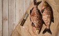 Two fish-bream Abramis, cleaned of scales on craft paper, lie on a wooden background.