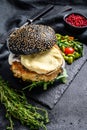 Home craft Burger with a black bun, scrambled eggs, and arugula. Blackburger. Black background. Top view Royalty Free Stock Photo