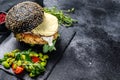 Home craft Burger with a black bun, scrambled eggs, and arugula. Blackburger. Black background. Top view. Copy space Royalty Free Stock Photo