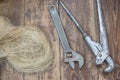 Home craftsman`s tool. Top view wrenches, adjustable wrench, pipe wrench, plumbing flax on wooden vintage background. Home plumbi