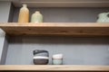 Home decor - various neutral colored vases wooden shelf against grey wall.