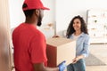 Black delivery man giving box to woman standing at door Royalty Free Stock Photo