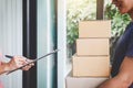 Home delivery service and working with service mind, Woman customer signing and receiving a cardboard boxes parcel from Royalty Free Stock Photo