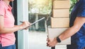 Home delivery service and working with service mind, Woman customer signing and receiving a cardboard boxes parcel from Royalty Free Stock Photo