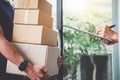 Home delivery service and working with service mind, Woman customer signing and receiving a cardboard boxes parcel from Royalty Free Stock Photo