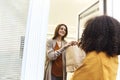 Home delivery. Woman opening house entrance door while meeting courier with online order