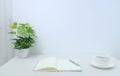 Home desk with notebook, pen, cup and potted plant Royalty Free Stock Photo