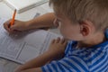 Home education. Home work after school. Boy with pen writing english test by hand on traditional white notepad paper. Royalty Free Stock Photo