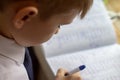 Home education. Home work after school. Boy with pen writing english words by hand on traditional white notepad paper. Royalty Free Stock Photo