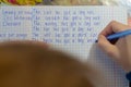 Home education. Home work after school. Boy with pen writing english test by hand on traditional white notepad paper. Royalty Free Stock Photo