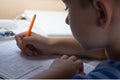 Home education. Home work after school. Boy with pen writing english test by hand on traditional white notepad paper. Royalty Free Stock Photo