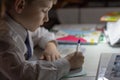 Home education. Home work after school. Boy with pen writing english words by hand on traditional white notepad paper. Royalty Free Stock Photo