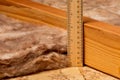 Measuring fiberglass insulation with ruler in attic of house. Royalty Free Stock Photo