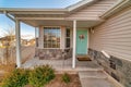 Home facade featuring open concrete porch bay window and pastel green door Royalty Free Stock Photo