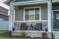 Home facade with porch and front door decorated with potted plants and wreath