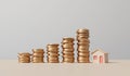 Home finance and property investment concept. Small house with a rising stack of coins. 3D Rendering