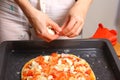 Making pizza by female hands on kitchen table.