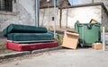 Home furniture thrown in the garbage on the street in the city near plastic dumpster cans littering and polluting the town and env