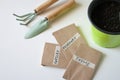 Home garden tools for planting, paper bags with seeds of parsley, thyme, rosemary. green pot with soil. Vegetables for balcony