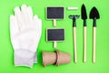 Home gardening. Miniature gardening tools: scoop, rake, inscription board, gloves and chalk on green cardboard