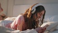 Home girl listening headphones in sunlight closeup. Carefree model lying bed