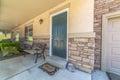 Home with green door yard windows and porch bench against stone brick wall Royalty Free Stock Photo