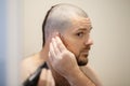 Home haircut, a man cuts his head with a clipper in front of a mirror Royalty Free Stock Photo