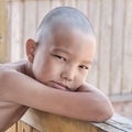 Portrait of tanned asian boy, hair cut bald, looking at camera