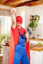 Home hero. A husband dressed as a superhero fixes furniture in the kitchen and poses with a drill in his hand. Funny repairman Royalty Free Stock Photo