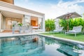 Home or house Exterior design showing tropical pool villa with greenery garden, sun bed, umbrella, pool towels Royalty Free Stock Photo