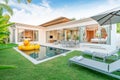 Home or house Exterior design showing tropical pool villa with greenery garden, sun bed, umbrella, pool towels and floating duck Royalty Free Stock Photo