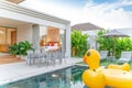 Home or house Exterior design showing tropical pool villa with greenery garden, sun bed, umbrella, pool towels and floating duck Royalty Free Stock Photo