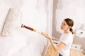 Home improvement. Beautiful woman painting wall with paint roller.