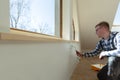 Home improvement concept, handyman painting a wall with a white paint near roof window in attic Royalty Free Stock Photo