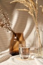 Glass of water, decorative dried flowers in vases