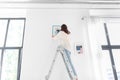 woman on ladder decorating home with art