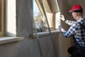 Home improvement handyman installing window in new build attic by using leveler and laser leveler Royalty Free Stock Photo