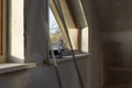 Home improvement handyman installing window in new build attic by using leveler and laser leveler Royalty Free Stock Photo