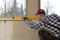 Home improvement handyman installing window sill in new build attic by using leveler and laser leveler