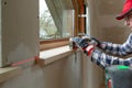 Home improvement handyman installing window sill in new build attic by using leveler and laser leveler Royalty Free Stock Photo