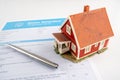 Home insurance proposal form with miniature red house and pen laying on white office desk. Royalty Free Stock Photo