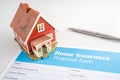 Home insurance proposal form with miniature red house and pen laying on white office desk. Royalty Free Stock Photo