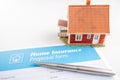 Home insurance proposal form with miniature red house and pen laying on white office desk Royalty Free Stock Photo