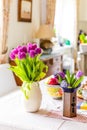 Home interior decoration. Purple tulips flowers in vase on kitchen table next to window Royalty Free Stock Photo