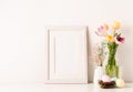 Mockup with a white frame spring tulips in vase, gypsophila and pastel colored eggs on light background Royalty Free Stock Photo